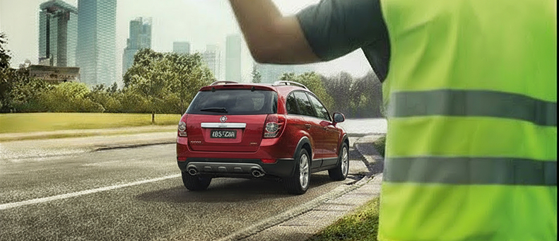Roadside technician fitting a new car battery to a Holden