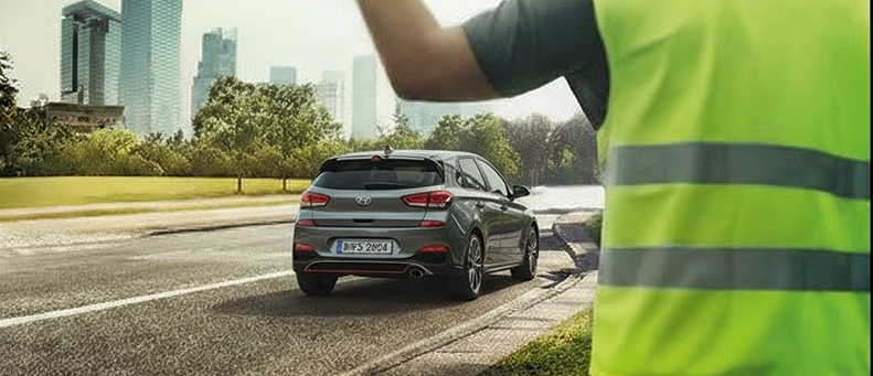 Roadside technician fitting a new car battery to a Hyundai