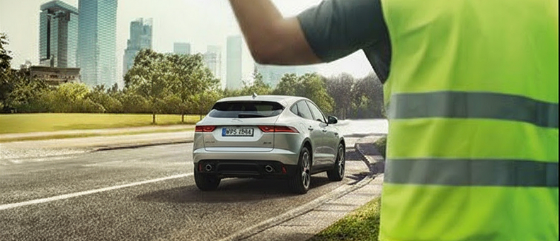Roadside technician fitting a new car battery to a Jaguar