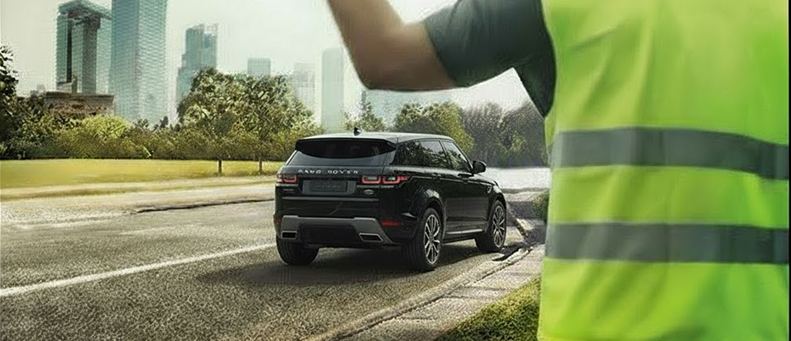 Roadside technician fitting a new car battery to a Land Rover