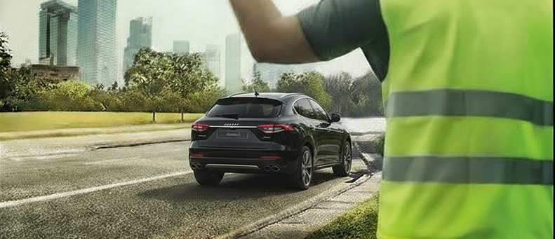 Roadside technician fitting a new car battery to a Maserati