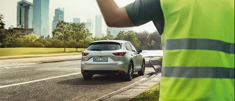 Roadside technician fitting a new car battery to a Mazda