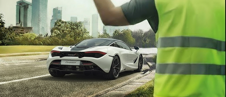 Roadside technician fitting a new car battery to a McLaren