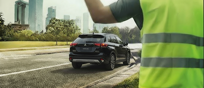 Roadside technician fitting a new car battery to a Mitsubishi