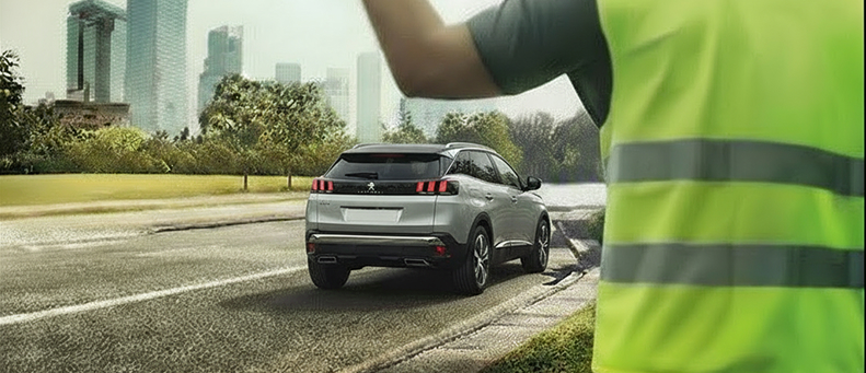 Roadside technician fitting a new car battery to a Peugeot