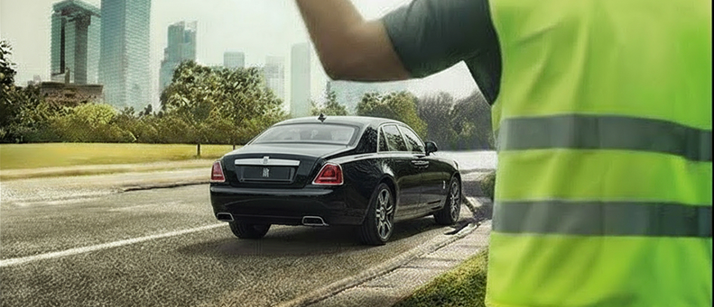 Roadside technician fitting a new car battery to a Rolls Royce