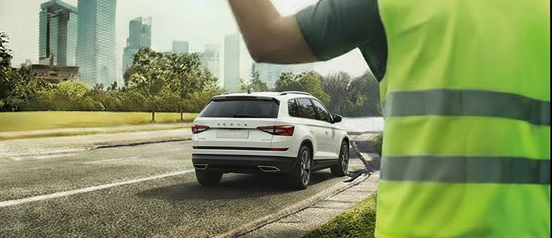 Roadside technician fitting a new car battery to a Skoda