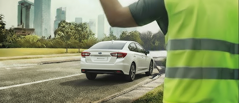 Roadside technician fitting a new car battery to a Subaru
