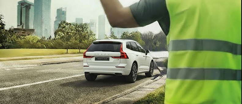 Roadside technician fitting a new car battery to a Volvo