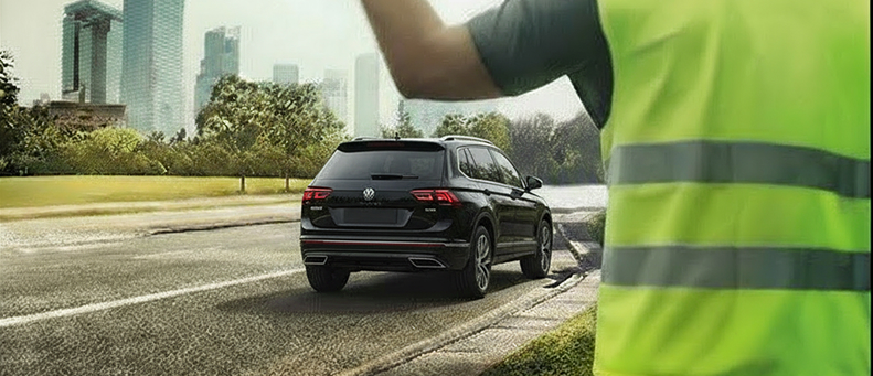 Roadside technician fitting a new car battery to a Volkswagen
